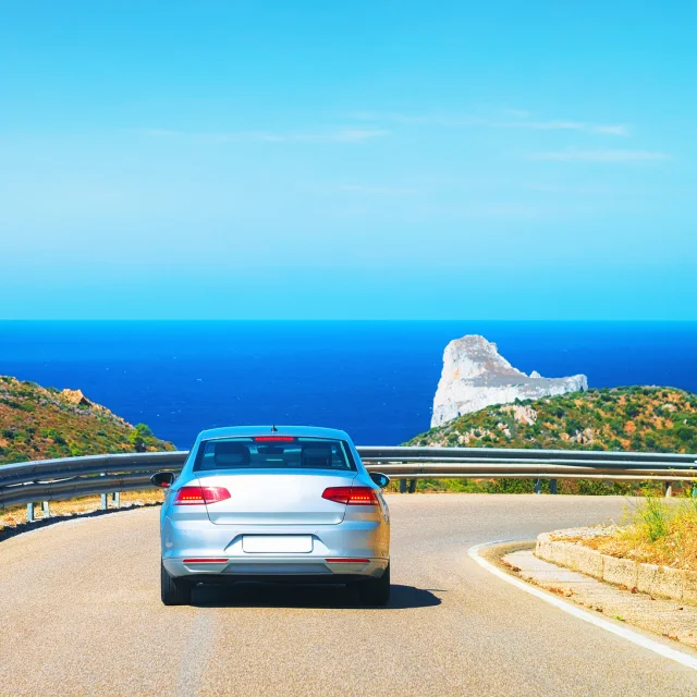 Car on the road at Porto Corallo in Nebida with the Mediterranean Sea, Carbonia-Iglesias, Sardinia, Italy