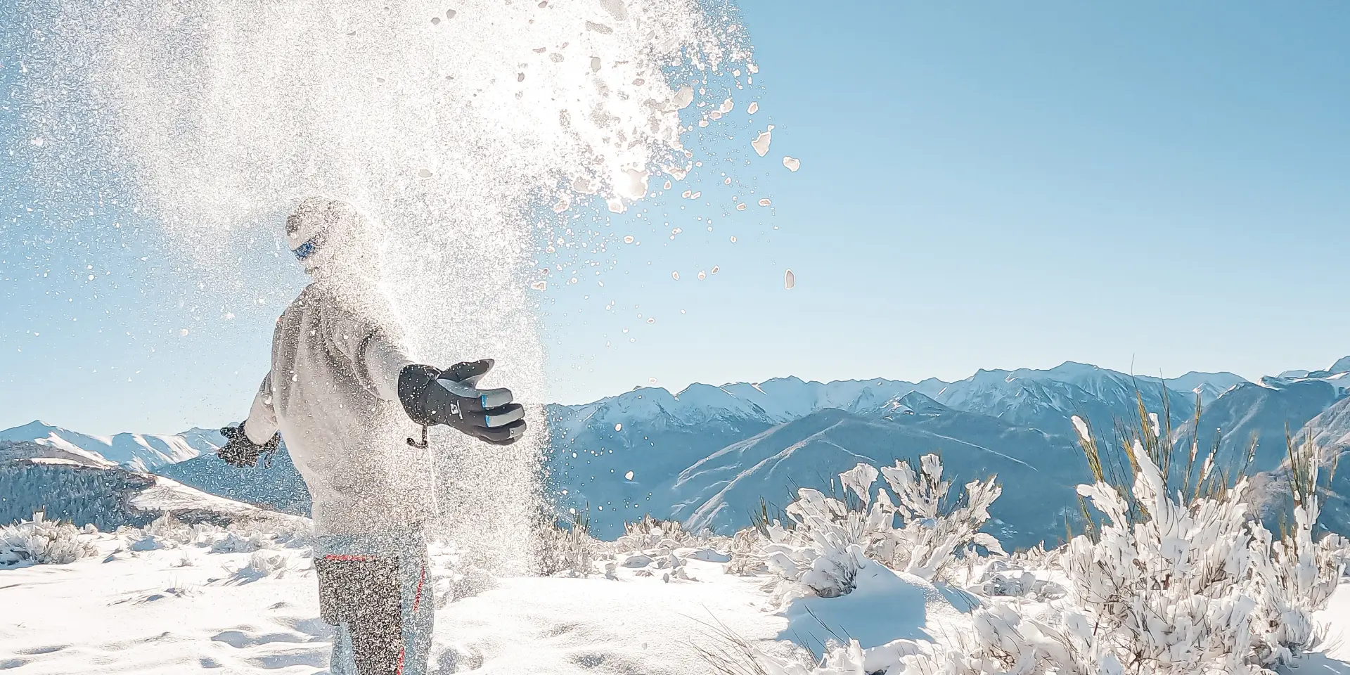 Personne lançant de la neige en montagne avec des paysages enneigés
