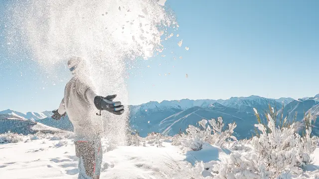 Person throwing snow in the mountains with snowy landscapes