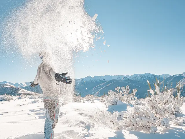 Persona lanzando nieve en la montaña con paisajes nevados