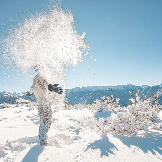 Personne lançant de la neige en montagne avec des paysages enneigés
