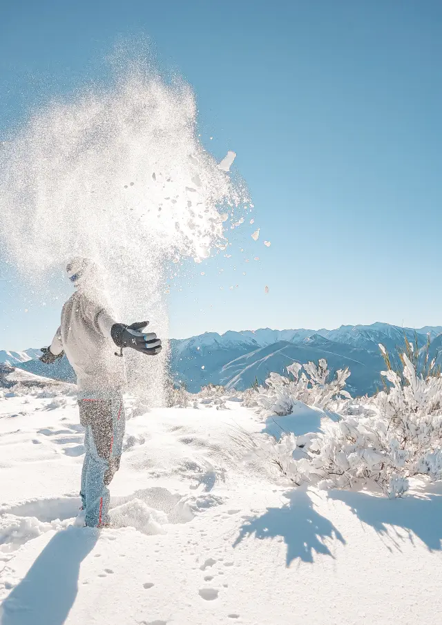 Personne lançant de la neige en montagne avec des paysages enneigés
