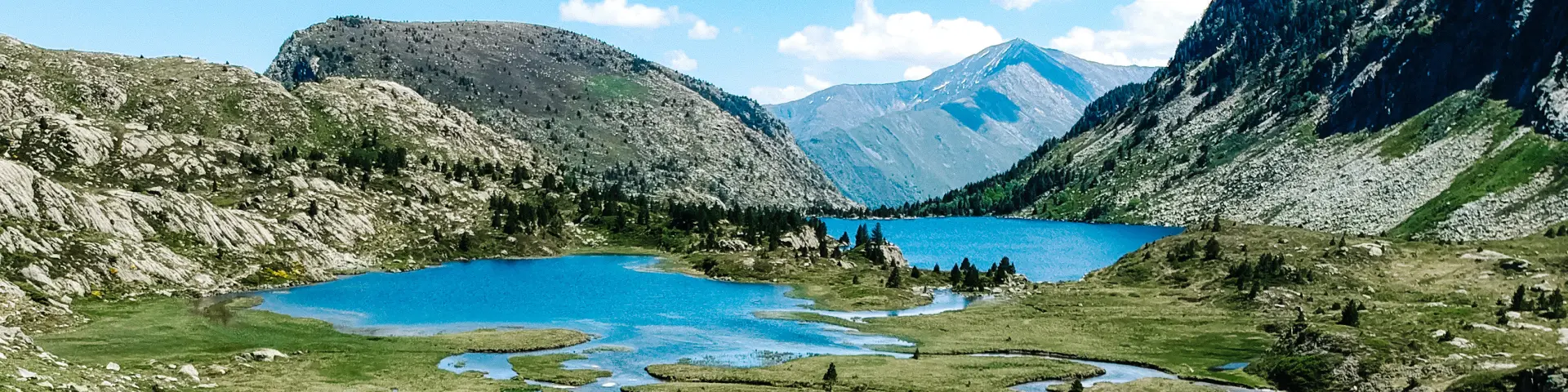 Un lago de montaña con una carretera sinuosa que cruza una pradera húmeda