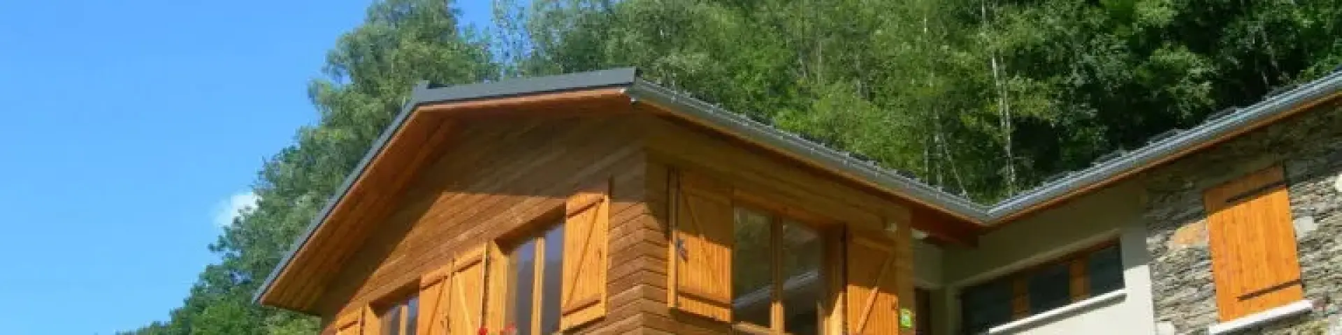 Wooden house with orange shutters on a green hillside