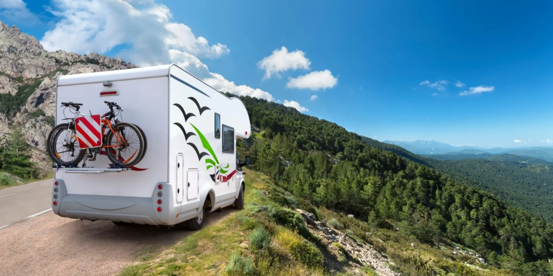 Autocaravana aparcada en el arcén de una carretera de montaña con bicicletas en la parte trasera