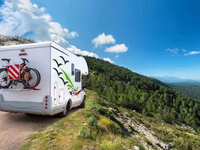 Autocaravana aparcada en el arcén de una carretera de montaña con bicicletas en la parte trasera