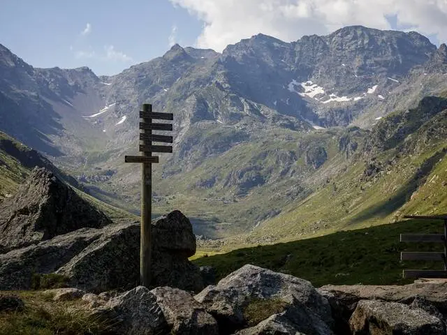 Posto indicador de madera con varias direcciones en un paisaje montañoso