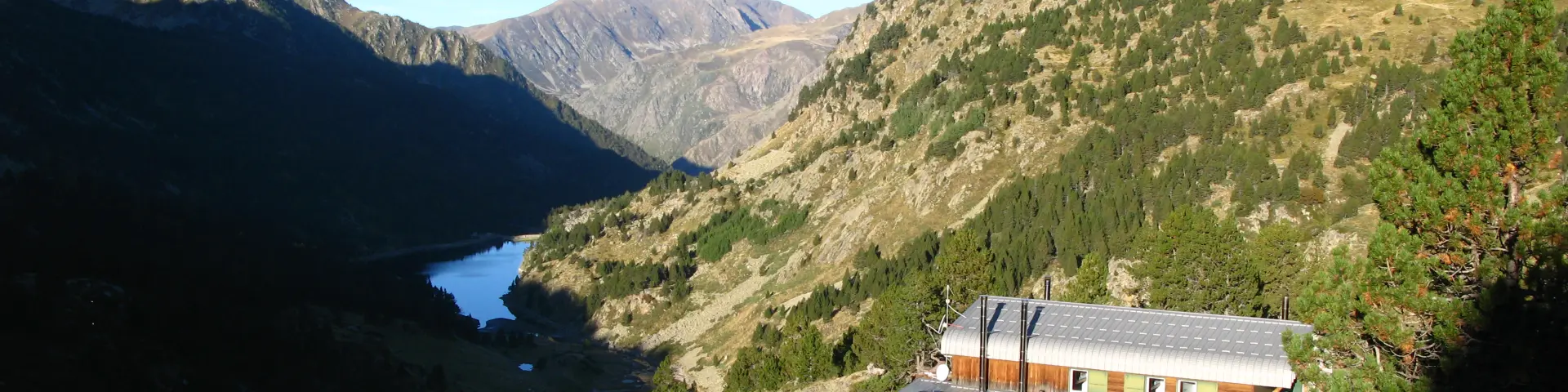An isolated mountain refuge surrounded by mountainous landscapes and a lake