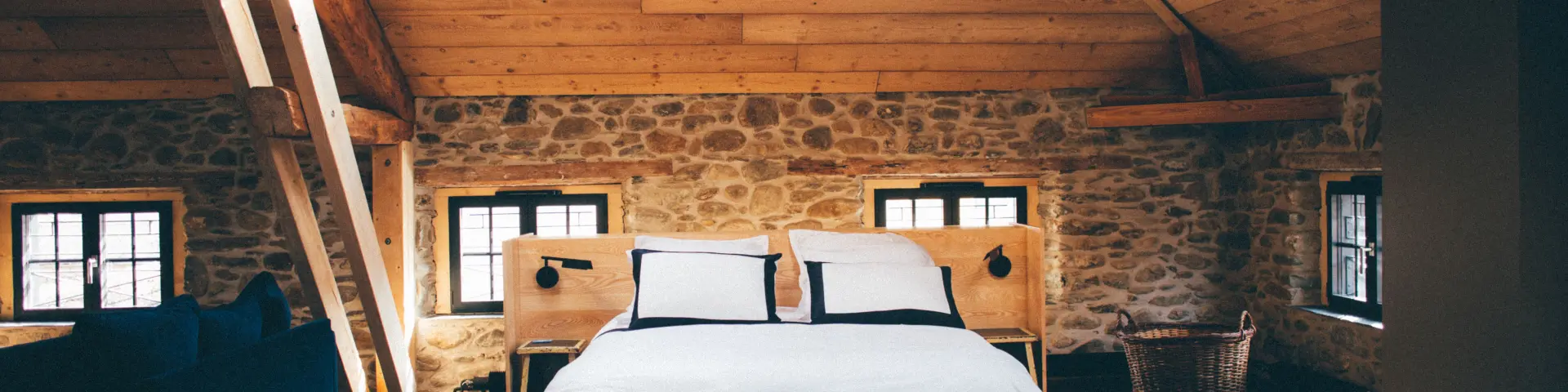 Bedroom with double bed, stone walls, and wooden ceiling