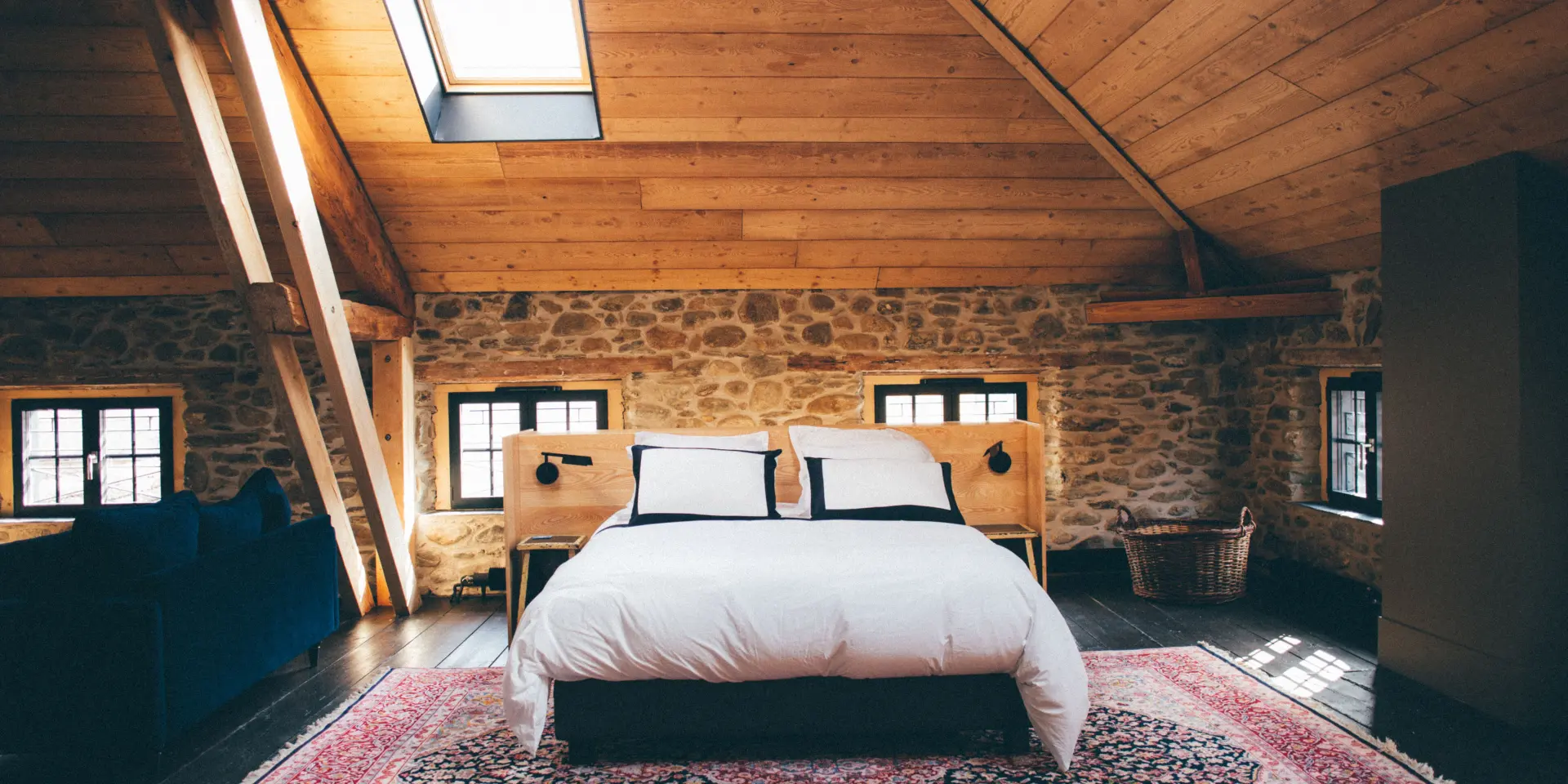 Dormitorio con cama doble, paredes de piedra y techo de madera