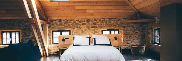 Bedroom with double bed, stone walls, and wooden ceiling
