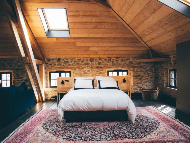 Bedroom with double bed, stone walls, and wooden ceiling