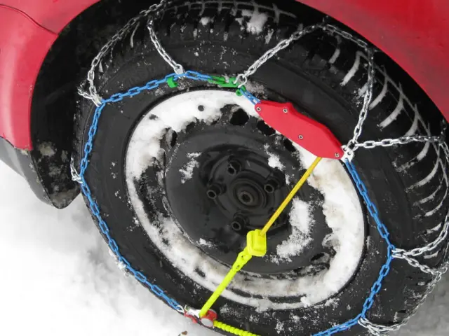 Car tires covered in snow with anti-skid chains