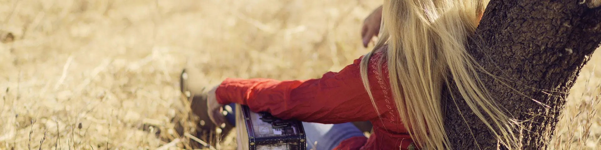 Blonde child sitting in a field with an animal