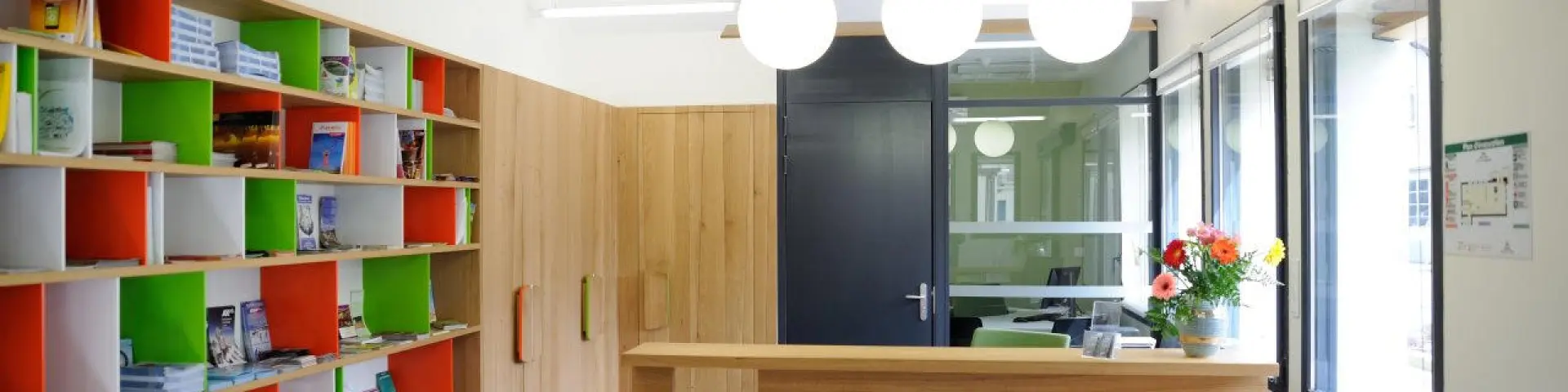 Interior of a library with colorful shelves and a wooden reception desk