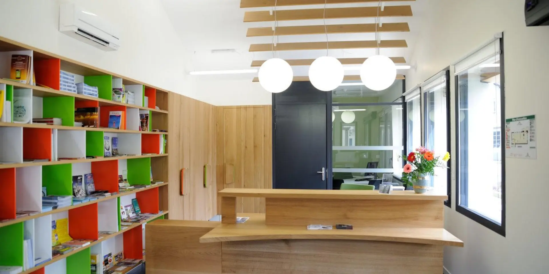 Intérieur d'une bibliothèque avec des étagères colorées et un bureau d'accueil en bois