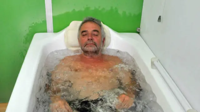 Elderly man in a hot tub with murky water