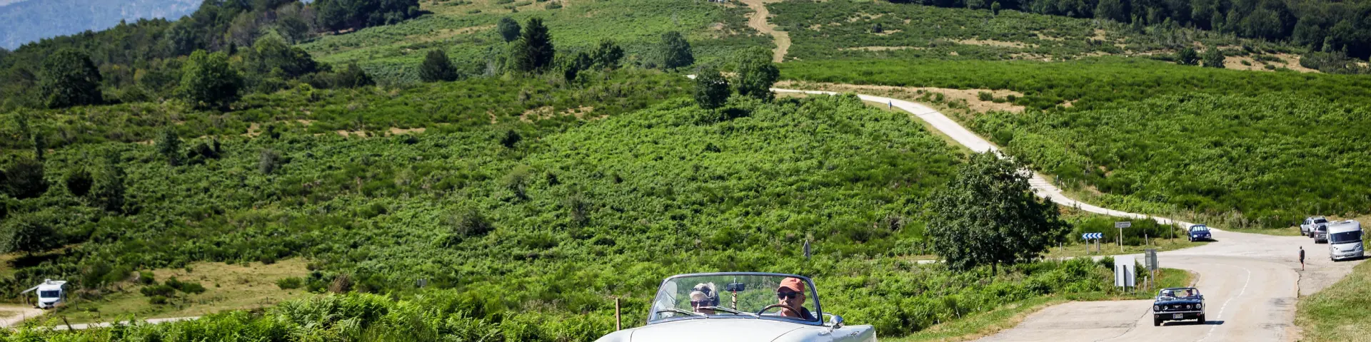 Vintage car on a countryside road with green hills
