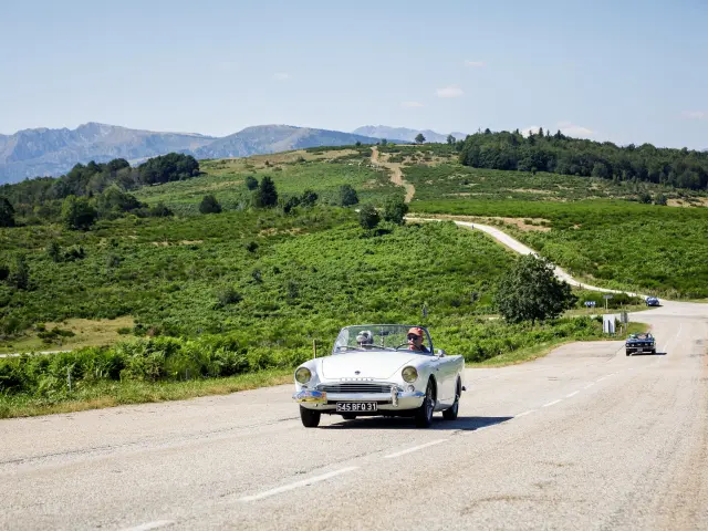 Vintage car on a countryside road with green hills