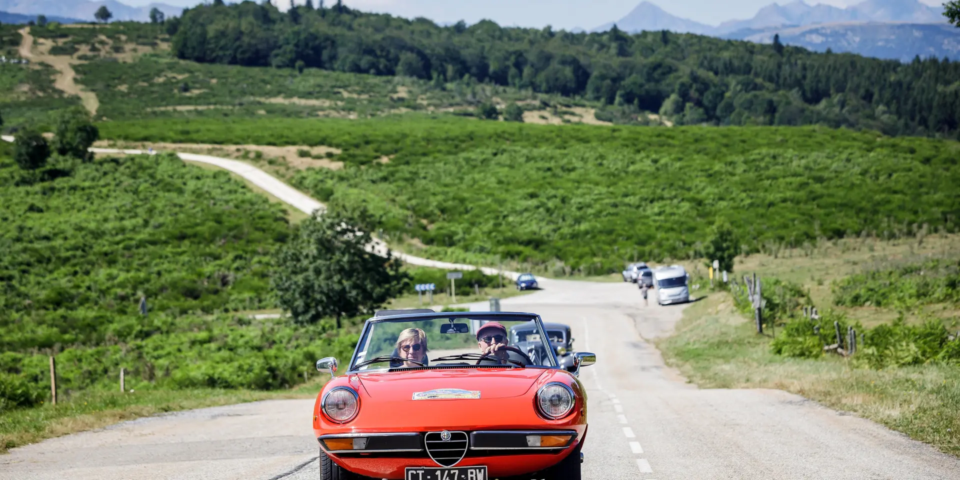 Red Alfa Romeo convertible driving on a country road