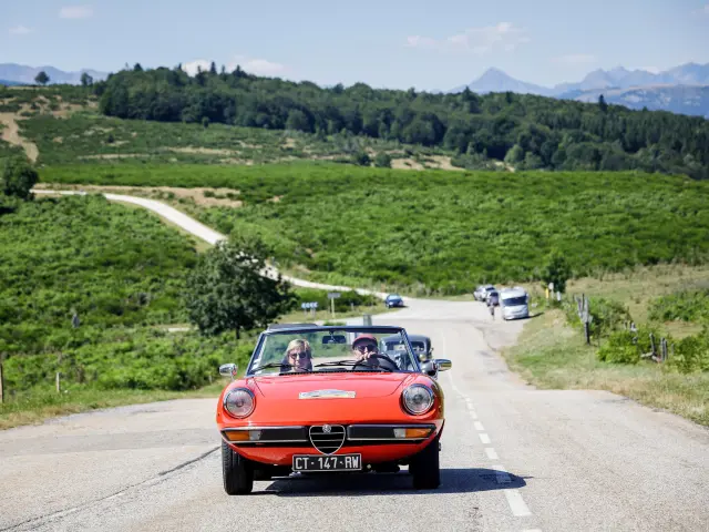 Red Alfa Romeo convertible driving on a country road