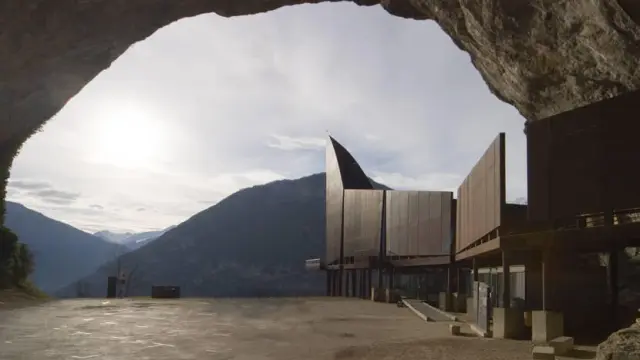Bâtiment moderne situé à l'intérieur d'une grotte avec des montagnes en arrière-plan