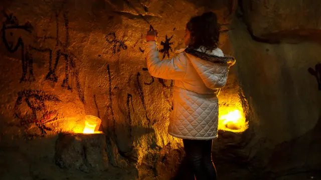 Une personne examine des peintures rupestres à la lueur de bougies