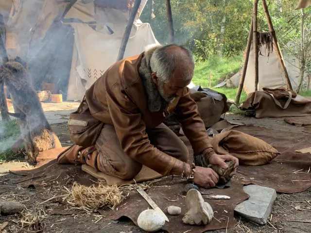 Un artisan façonne un outil en pierre avec des outils primitifs