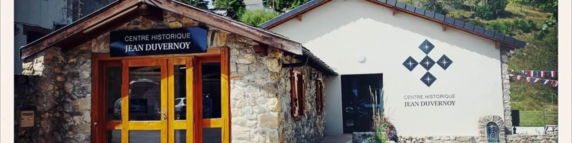 Stone building with an orange wooden door and a sign reading Jean Duvernoy Historical Center