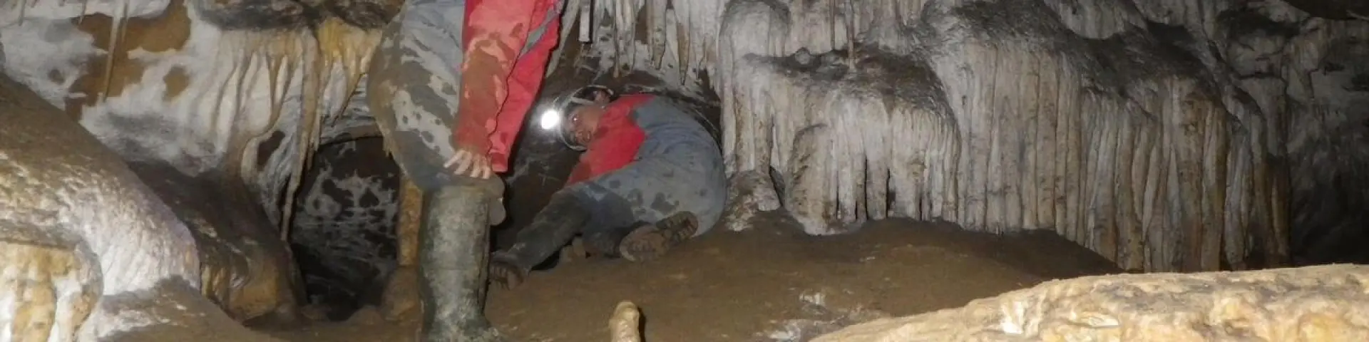Person exploring a cave with stalactites and stalagmites