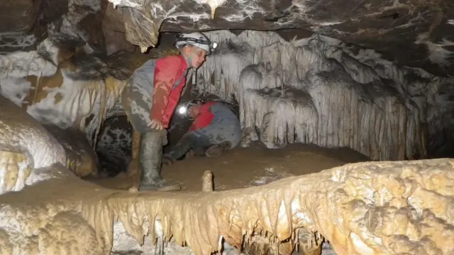 Person exploring a cave with stalactites and stalagmites