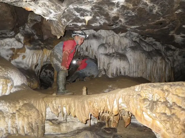 Persona explorando una cueva con estalactitas y estalagmitas