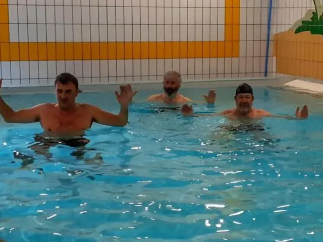 Cinq hommes nageant dans une piscine intérieure