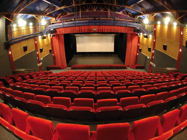 Movie theater with red seats and a white screen