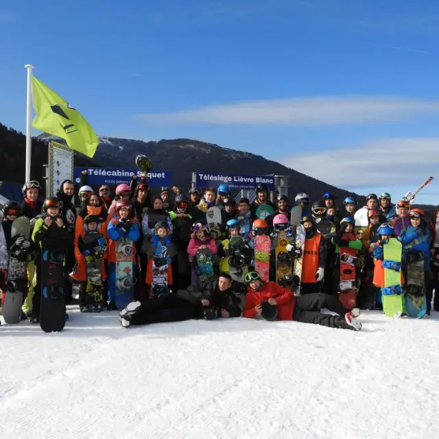 Groupe de personnes avec des snowboards posant devant une station de ski