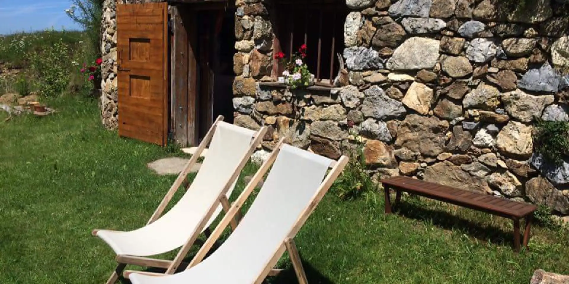 Orry en pierre avec deux chaises longues blanches et une table en bois