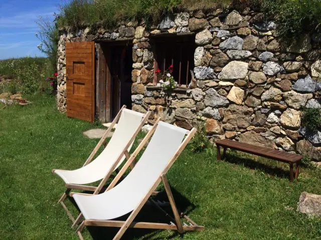 Orry en pierre avec deux chaises longues blanches et une table en bois