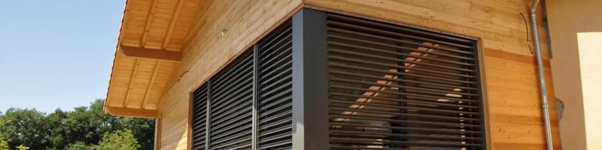 Maison en bois avec une grande terrasse en bois et des volets fermés