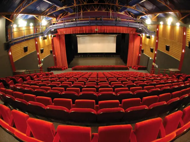 Movie theater with red seats and a white screen