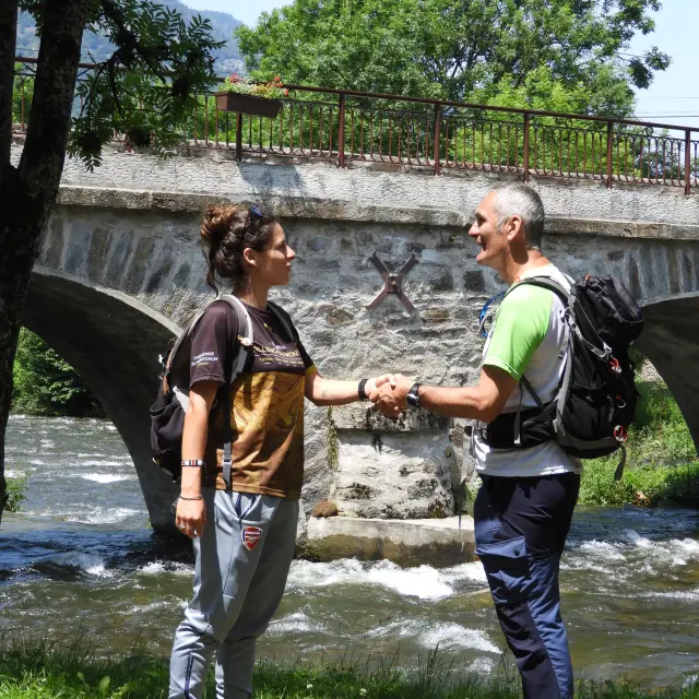 Two people shaking hands near a river