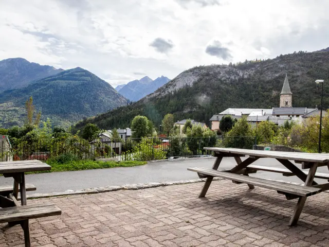 Village surrounded by mountains with picnic tables in the foreground