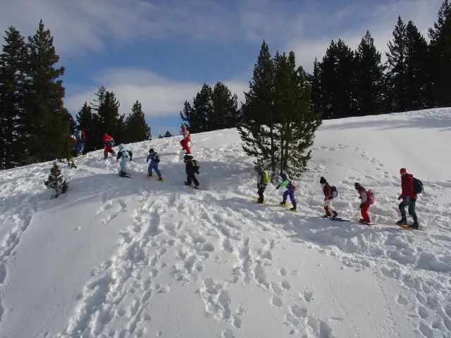 Group of children walking in the snow with snowshoes