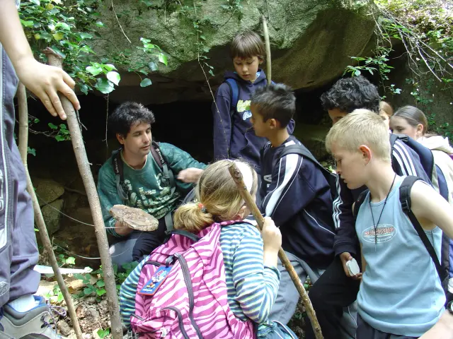 A group of children exploring a cave with a guide