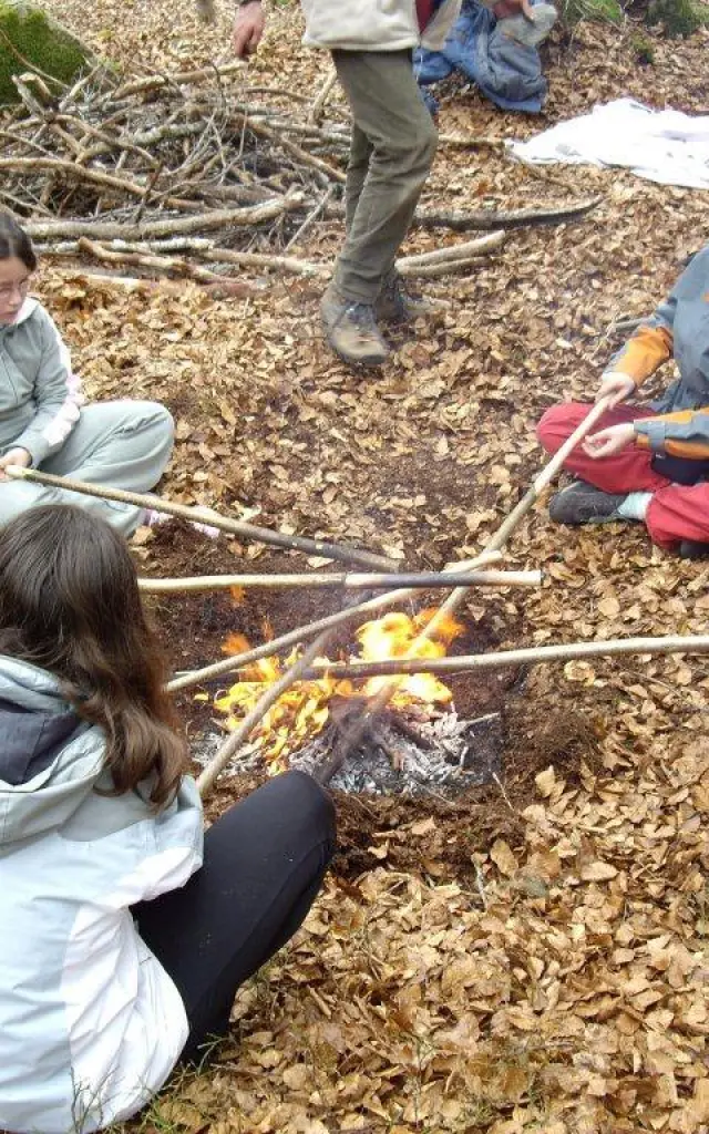 Un groupe d'enfants assis autour d'un feu de camp en forêt