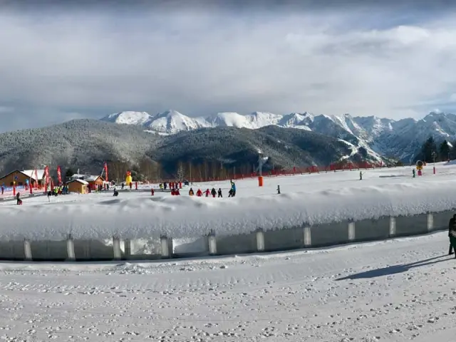 Panoramic view of a ski resort with snowy slopes and mountains in the background