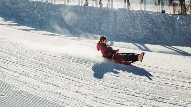 Child going down a snowy slope on a sled