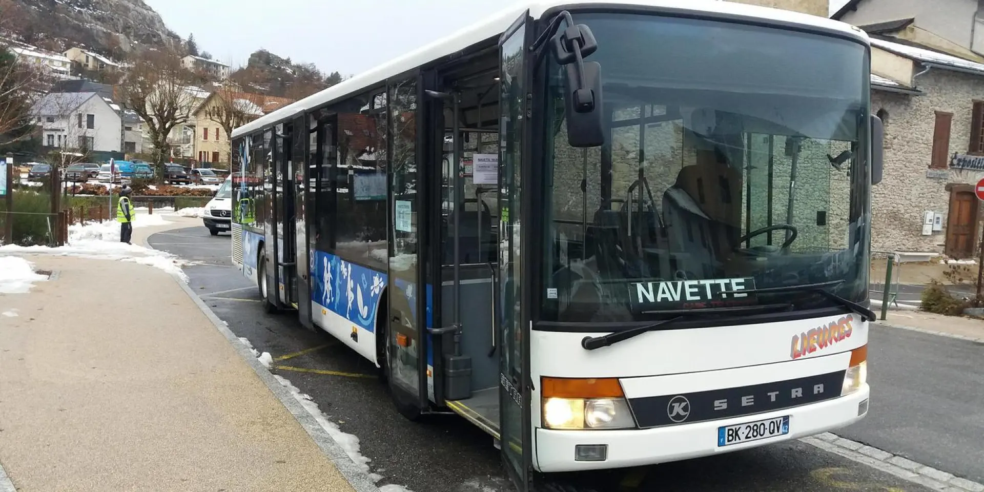 Un bus navette blanc stationné sur le côté d'une route enneigée