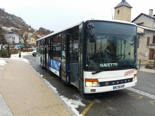Un bus navette blanc stationné sur le côté d'une route enneigée