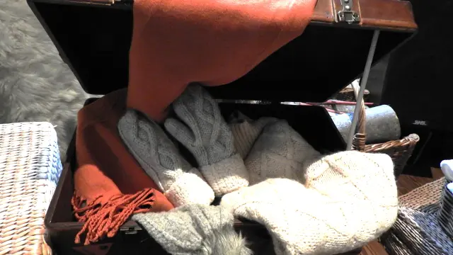 A wooden chest filled with gloves, scarves, and a hat