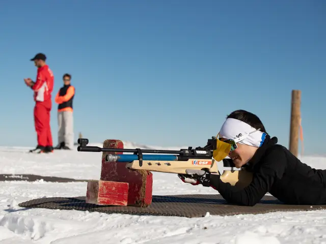Un biathlète en position de tir couché sur la neige